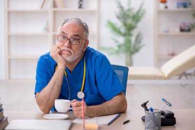 Yaşlı doktor molada kahve içiyor.