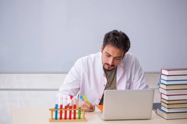 Genç kimyacı öğretmen beyaz tahtanın önünde.