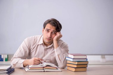 Sınıfta oturan genç öğretmen.