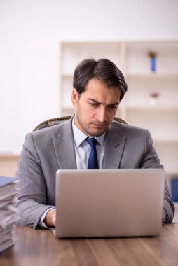 Genç işadamı ve işyerinde çok fazla iş var.