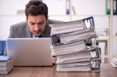 Young employee and too much work at workplace