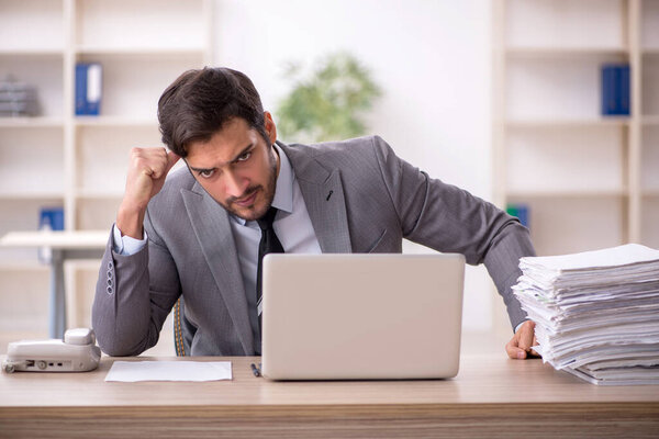 Молодой бизнесмен и слишком много работы в офисе