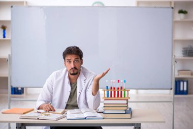 Genç kimyacı öğretmen beyaz tahtanın önünde.