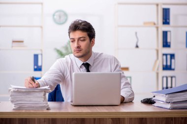 Young employee and too much work at workplace