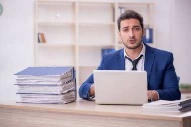 Genç işadamı ve işyerinde çok fazla iş var.