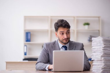 Young employee and too much work at workplace