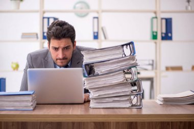 Young employee and too much work at workplace