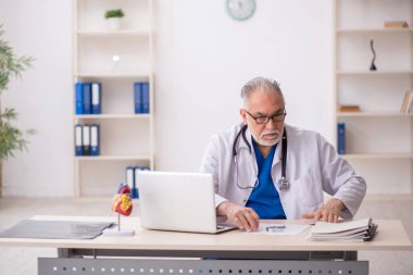 Klinikte çalışan yaşlı bir doktor.