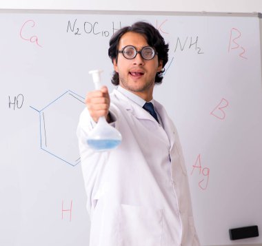 Beyaz panonun önündeki komik genç kimyager.