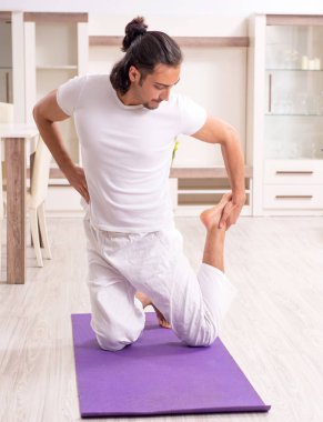 Genç adam evde fiziksel egzersiz yapıyor.