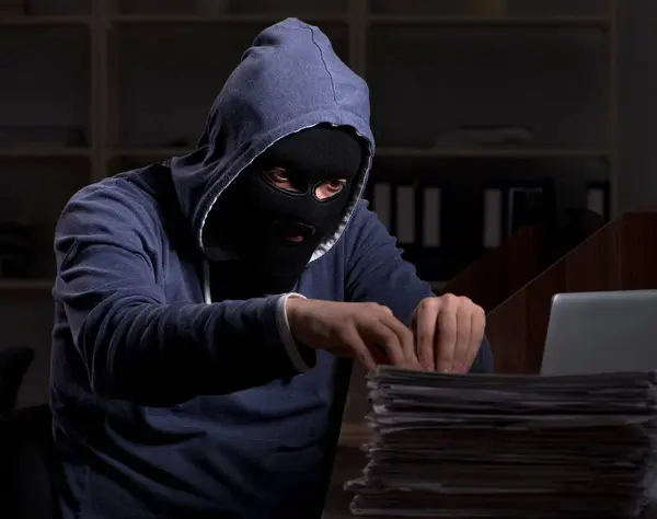The male thief in balaclava in the office night time