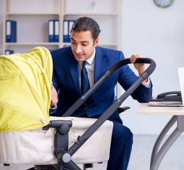 Ofiste yeni doğan bebeğe bakan genç baba.