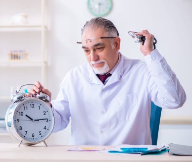 Klinikte çalışan yaşlı erkek doktor.