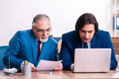 Genç ve yaşlı çalışanlar ofiste birlikte çalışıyorlar.