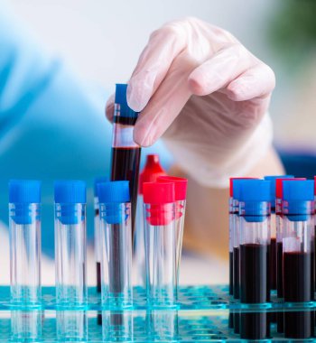 Genç laboratuvar asistanı hastanede kan örneklerini test ediyor.