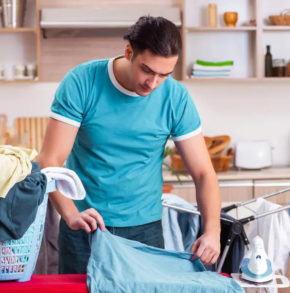 stock image The young man husband doing clothing ironing at home