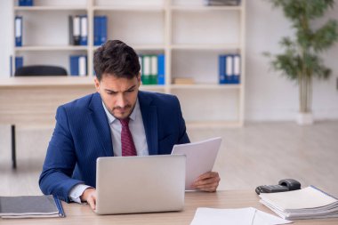 Genç işadamı işyerinde oturuyor.