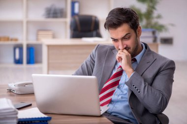 Genç işadamı işyerinde oturuyor.