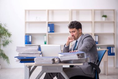 Young employee and too much work at workplace