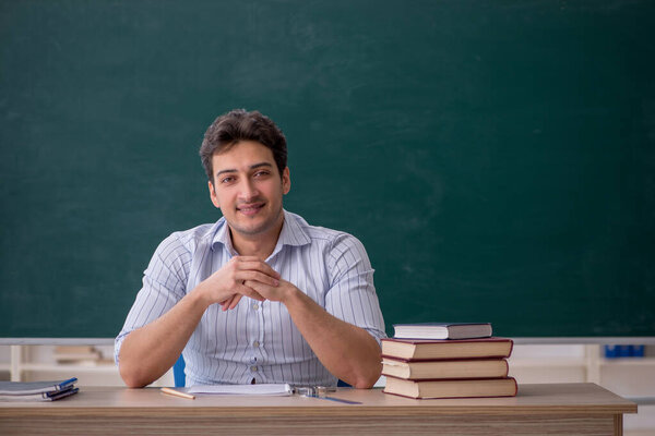 Young teacher in front of green board