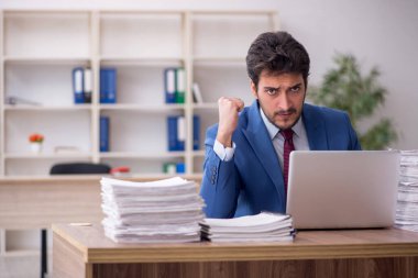 Young employee and too much work at workplace