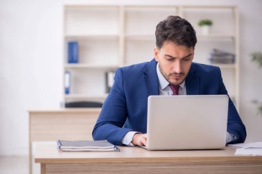 Genç işadamı işyerinde oturuyor.