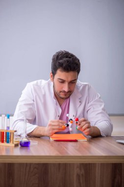 Young chemistry teacher sitting in the classroom