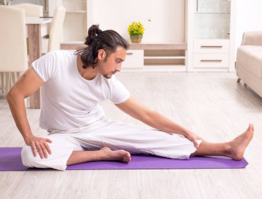 Genç adam evde fiziksel egzersiz yapıyor.