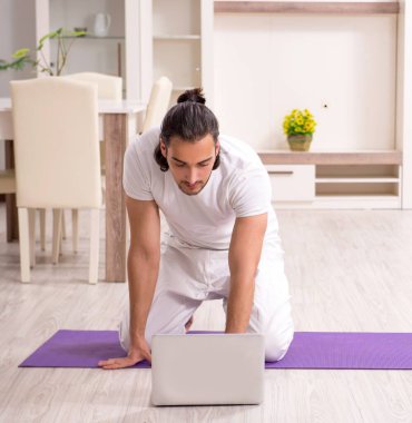 Genç adam evde fiziksel egzersiz yapıyor.