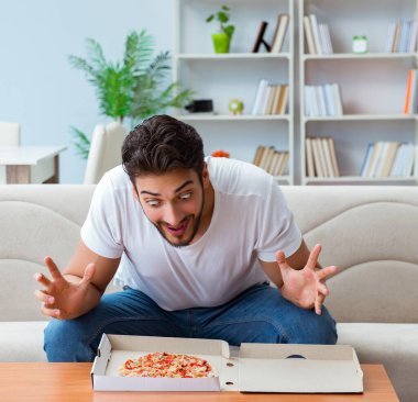 Pizza yiyen adam evde yemek yiyor, dinleniyor.