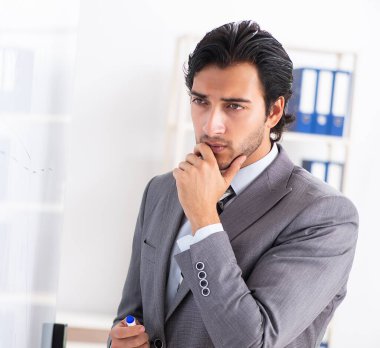 Genç yakışıklı iş adamı beyaz tahtanın önünde.