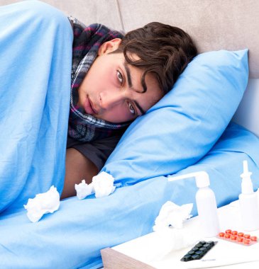 Grip olmuş hasta adam yatakta yatıyor.