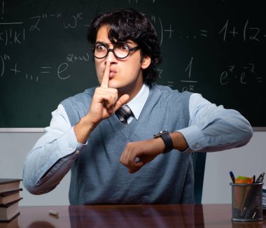 Tahtanın önündeki genç matematik öğretmeni.