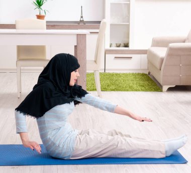 Tesettürlü genç kadın evde egzersiz yapıyor.