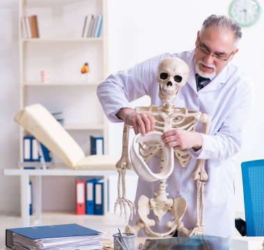 İskeleti olan yaşlı erkek doktor.