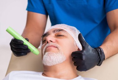 Yaşlı adam estetik ameliyat için doktoru ziyaret ediyor.