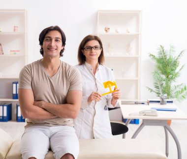 Kadın doktor hastaları goniyometre ile kontrol ediyor.