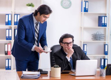 Patron ve erkek asistanı ofiste çalışıyor.