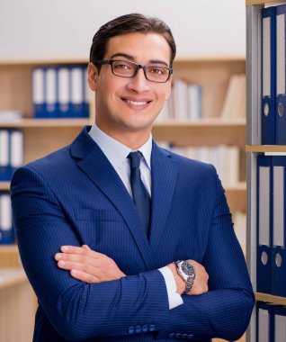 Rafın yanında duran yakışıklı iş adamı.