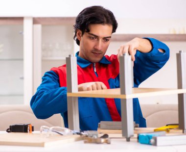 Genç müteahhit evde mobilya tamir ediyor.