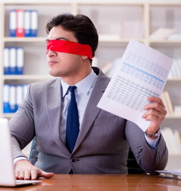 Ofiste masasında oturan gözü bağlı iş adamı.