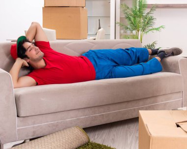 İçeride çalışan kutularla çalışan genç bir erkek müteahhit.