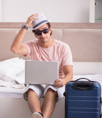 Yatak odasında bavullu adam geziyi bekliyor.