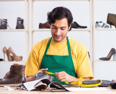 Atölyede ayakkabı tamir eden genç adam.