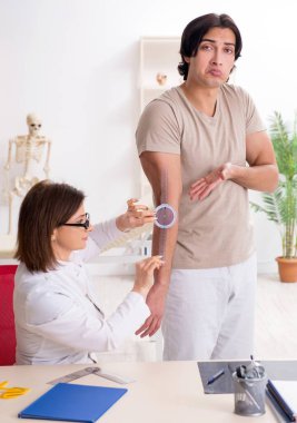 Kadın doktor hastaları goniyometre ile kontrol ediyor.