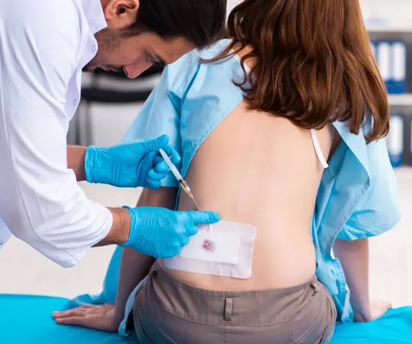 Yaralı genç kadın erkek doktoru ziyaret ediyor.