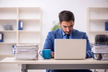 Genç işadamı ve işyerinde çok fazla iş var.