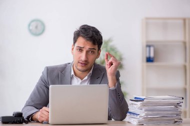 Young employee and too much work at workplace