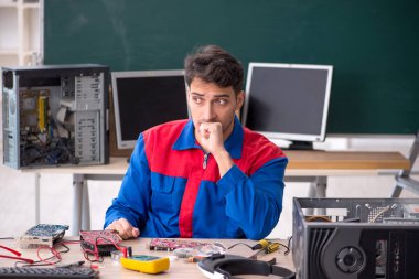 Sınıfta bilgisayar tamir eden genç bir tamirci.