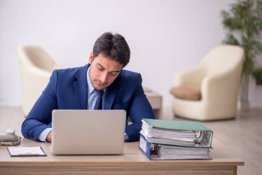 Genç işadamı işyerinde oturuyor.